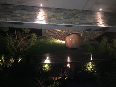raised bed and spherical stone water feature accentuated with clever garden lighting