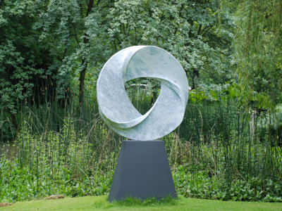 large abstract stone spherical garden sculpture on dark stone plinth